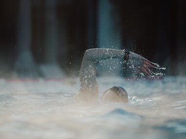 Swimmer turning in the water during swimming, water splashing around them. | © sportingWOMEN