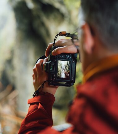Person taking a photo of a natural scenery in a forest with a digital camera. | © Evolumina