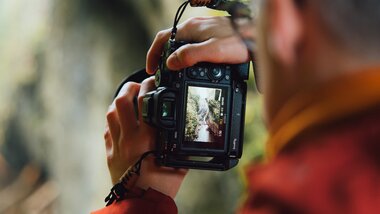 Person taking a photo of a natural scenery in a forest with a digital camera. | © Evolumina
