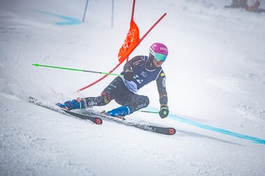 Skieracing athlete during the 2025 Ski & Golf World Championship, navigating a sharp turn on a groomed slope.