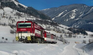 A train of the Pinzgauer Lokalbahn travels through a snowy winter landscape in the mountains. | © Salzburg AG