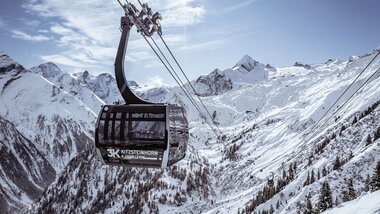 Cable car in snowy mountain landscape with high peaks and pine trees in the background. | © Kitzsteinhorn