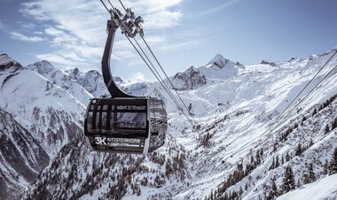 Cable car in snowy mountain landscape with high peaks and pine trees in the background. | © Kitzsteinhorn