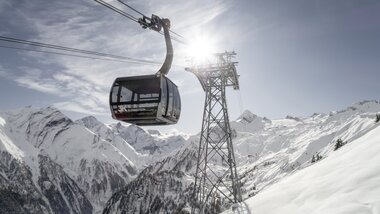 Cable car in the Alps with mountain peaks and a snow-covered valley in the background on a sunny day. | © Kitzsteinhorn