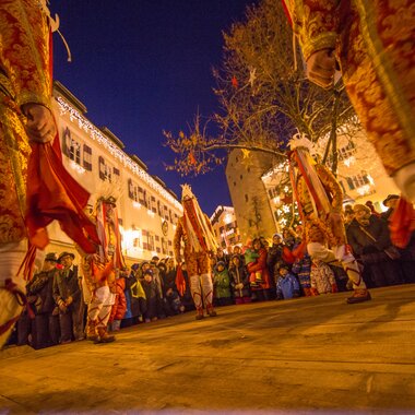 Traditional dance or celebration with dressed participants in Zell am See at night, with spectators in the background.