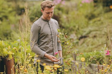 Person in a garden surrounded by colorful flowers, nature, and trees | © Zell am See-Kaprun Tourismus