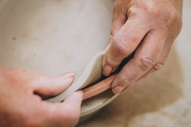 Close-up of hands shaping an unfinished clay pot in a pottery studio. | © Zell am See-Kaprun Tourismus