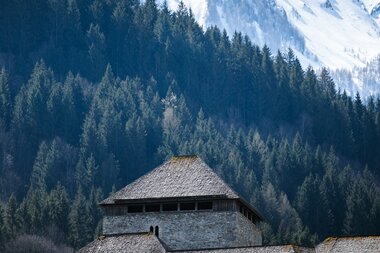 Historical building against a mountain backdrop with snow-capped peaks in spring. | © Zell am See-Kaprun Tourismus