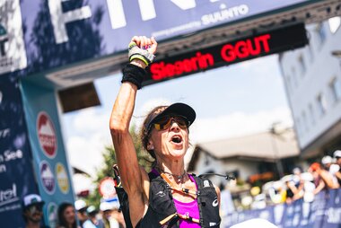 Winner of an ultra-marathon celebrating at the finish line, with banners and spectators in the background. | © Zell am See-Kaprun Tourismus