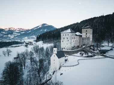 Santa Maria on a snowy hill with a castle in the background, set in a winter landscape in Kaprun. | © Zell am See-Kaprun Tourismus