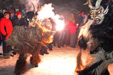 Kapruner Schiachperchten performing a fire dance during the 25th anniversary of the Raunacht at Burg Kaprun, with fire and traditional masks. | © Schweinoster