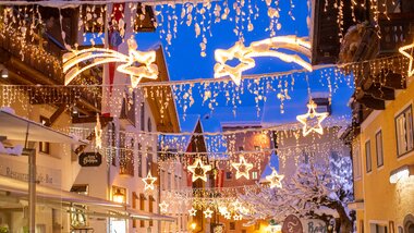 Decorated streets with string lights and stars, festive atmosphere at the winter market in Zell am See. | © Nikolaus Faistauer Photography