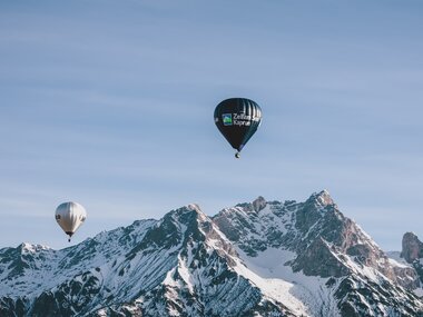 Multiple hot air balloons floating in front of snow-covered mountain peaks during Balloonalps 2024 near Zell am See-Kaprun. | © Zell am See-Kaprun Tourismus