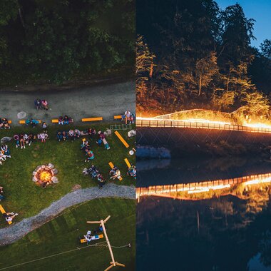 Campfire and people at a night event by the water, with a lit bridge in the background, reflected in the water. | © EXPA FEI