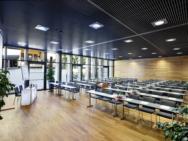 Modern seminar room with flexible seating, large windows, and wooden-paneled walls. | © Ferry Porsche Congress Center
