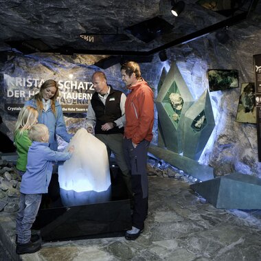 People exploring an exhibit in a cave-like environment with rocks and informational boards. | © Kitzsteinhorn 
