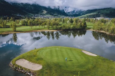 Panoramic view of a golf course near Zell am See, surrounded by water and mountains, featuring green fairways and sand bunkers. | © EXPA, Jürgen Feichter