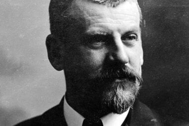 Black and white portrait of a man with a beard, formal attire, and short hair.