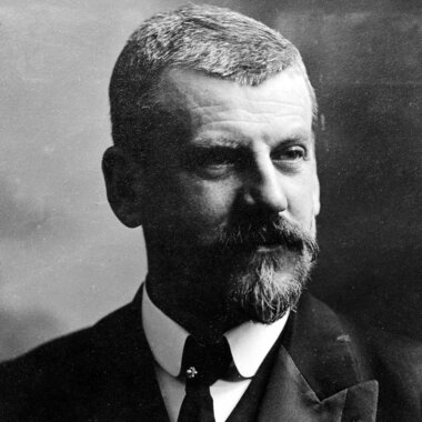 Black and white portrait of a man with a beard, formal attire, and short hair.