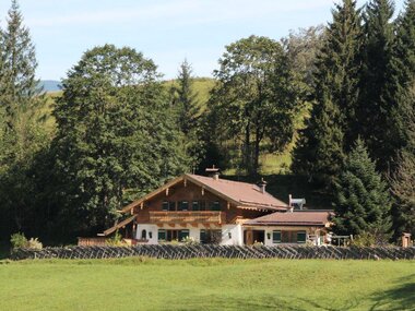 A house with wooden details, surrounded by forests and green land, peacefully situated in nature. | © Jagawirt Kaprun