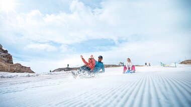 Skier and snowshoe hikers on a snow-covered slope with blue sky and clouds in the background. | © Kitzsteinhorn