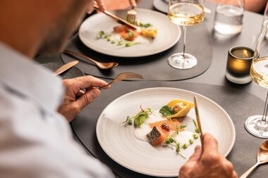 Elegant plated dish at a fine dining setting with wine and water, on a decorated table, contemporary presentation. | © Tauern SPA Zell am See-Kaprun