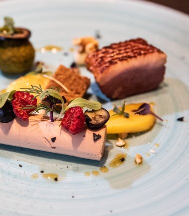 Elegant dish with poultry, side dishes, and garnishes on a blue ceramic plate | © Tauern SPA Zell am See-Kaprun