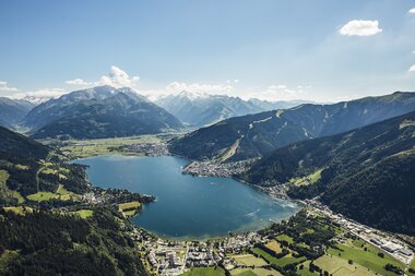 Aerial view of Zell am See and Lake Zell, surrounded by mountains and lush valleys in sunny weather. | © Zell am See-Kaprun Tourismus