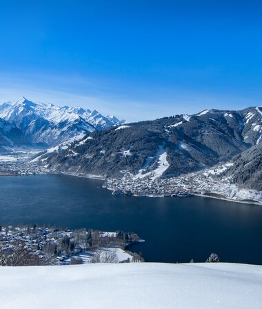 Winter landscape with a view of a lake surrounded by snow-covered mountains and hills. | © Nikolaus Faistauer