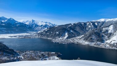 Winter landscape with a view of a lake surrounded by snow-covered mountains and hills. | © Nikolaus Faistauer