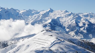 Aerial view of a snowy mountain landscape with high peaks and a clear blue sky. | © Zell am See-Kaprun Tourismus