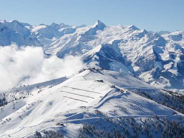 Aerial view of a snowy mountain landscape with high peaks and a clear blue sky. | © Zell am See-Kaprun Tourismus