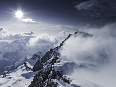 Winter mountain landscape with snow-covered slopes, clouds, and sunlight over Kitzsteinhorn. | © Kitzsteinhorn