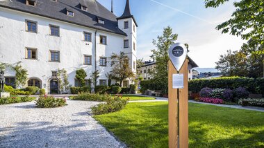Historic castle or building with white facade and green gardens in the foreground, sunny day | © Zell am See-Kaprun Tourismus, Dominik Wartbichler