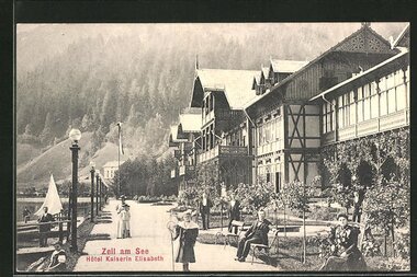 Vintage photo of Hotel Kaiserin Elisabeth in Zell am See with guests by the lake and garden, surrounded by mountains.