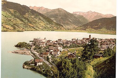 Historical image of Zell am See with lake, houses, and mountains in the background.