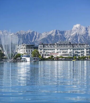 View of a hotel by a lake with mountain scenery in the background. | © Nikolaus Faistauer Photography