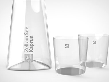 An elegant crystal glass carafe and two matching glasses, transparent and stylish, suitable for drinks. | © Zell am See-Kaprun & Studio F. A. Porsche