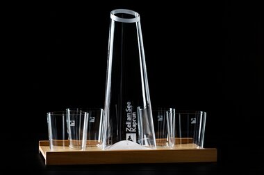 A stylish carafe and several glasses on a wooden tray against a black background. | © Nikolaus Faistauer Photography