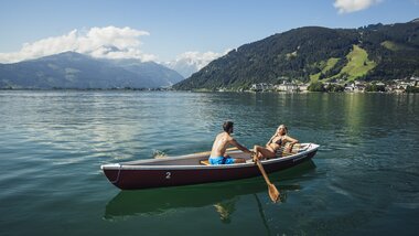 Two people in a rowing boat on a lake surrounded by mountains and blue sky. | © Zell am See-Kaprun Tourismus
