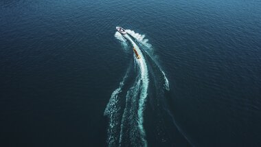 A boat speeding across Lake Zell, creating a trail on the water under sunny weather. | © Expa Pictures