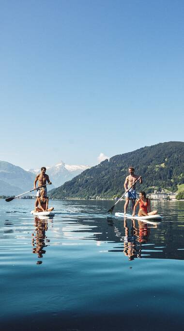 People stand-up paddling on Lake Zeller with mountainous scenery in the background. | © Zell am See-Kaprun Tourismus