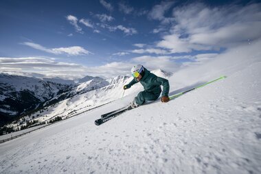 Skier skier in deep snow on a mountain slope under clear weather. | © saalbach.com, Stefan Voitl