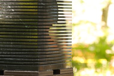 Sculpture in the sculpture park with horizontal metal slats and a view of the green surroundings.
