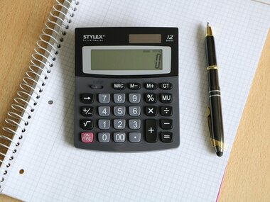 A calculator is placed on a spiral notebook with a black pen beside it. | © pixabay