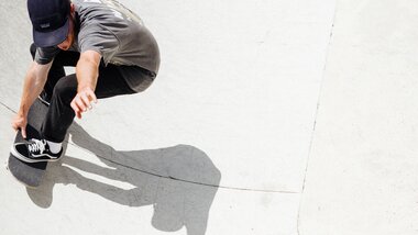 A skateboarder performing a trick in a skatepark, visible in their shadow on the ground.